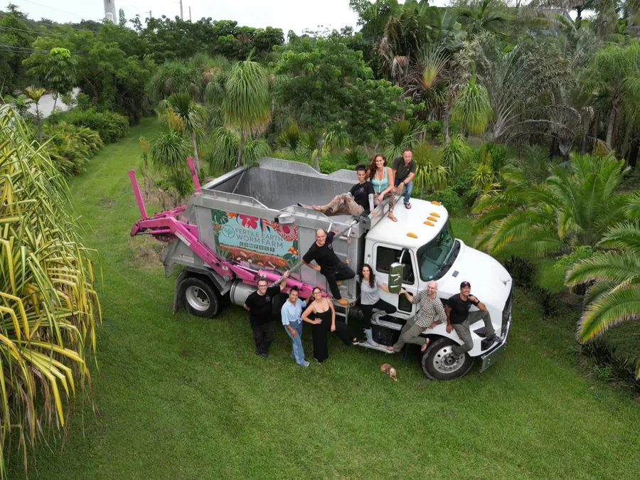 The Fertile Earth team posing on and around their pink-and-white food-scrap collection truck at the farm in Homestead