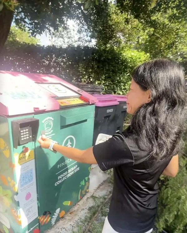 A resident dropping food scraps at a community compost collection site