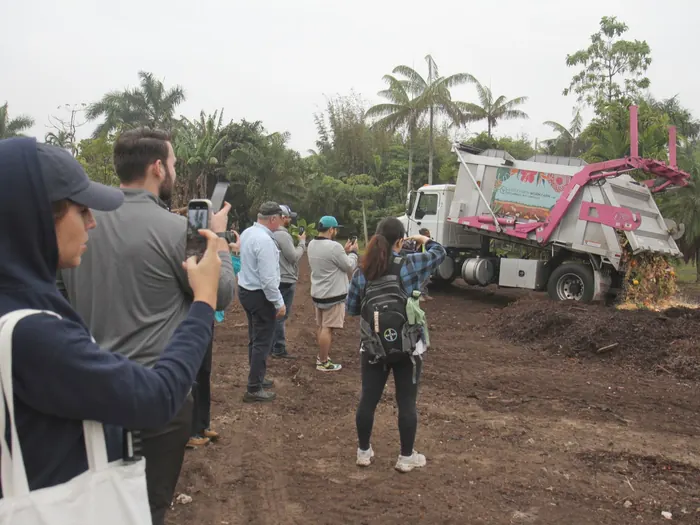 Guests on a Fertile Earth farm tour watching a demonstration near a collection truck