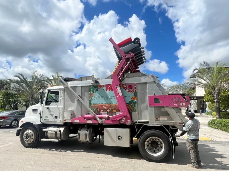 A Fertile Earth team member at a Village of Pinecrest community compost bin beside a collection truck