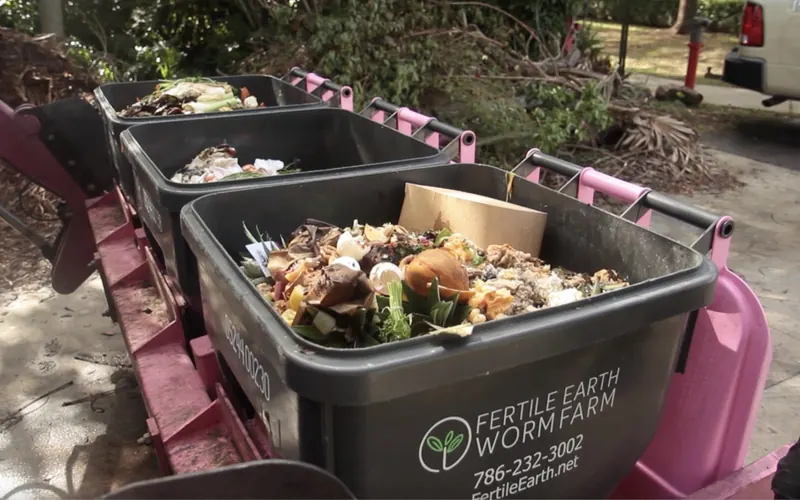 Fertile Earth food-scrap collection bins filled with organic material on a truck lift