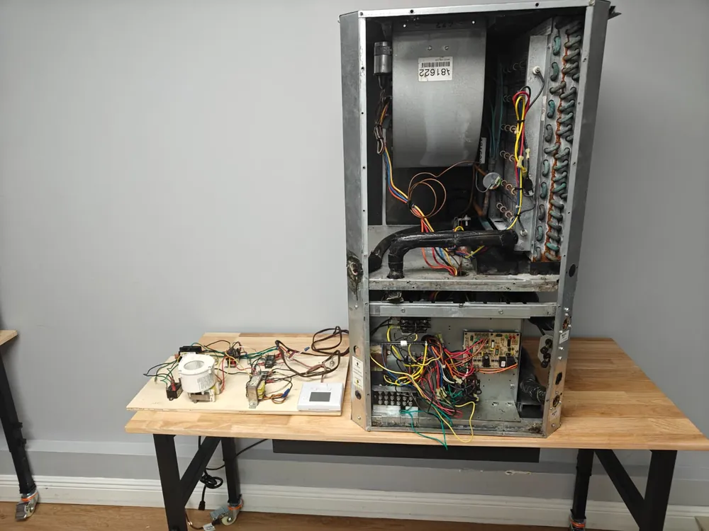 Opened air handler with its blower and wiring on a lab workbench at Florida Professional Institute