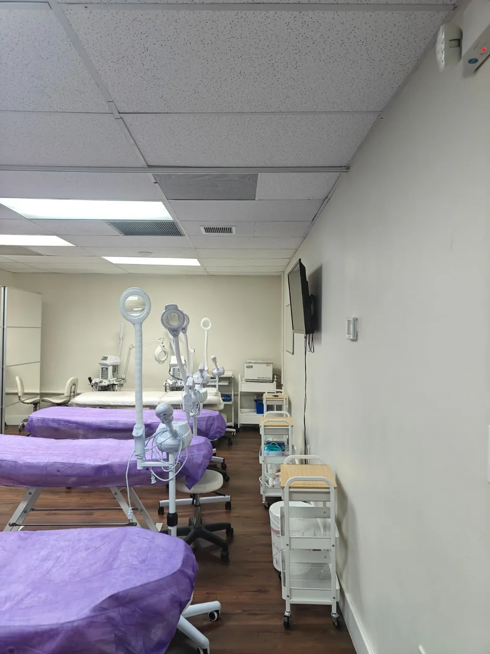 Treatment lab at Florida Professional Institute: rows of tables with purple covers, magnifying lamps and supply carts