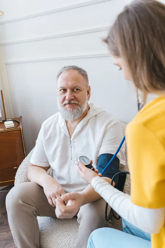 Home health nurse checking an elderly patient's blood pressure at home